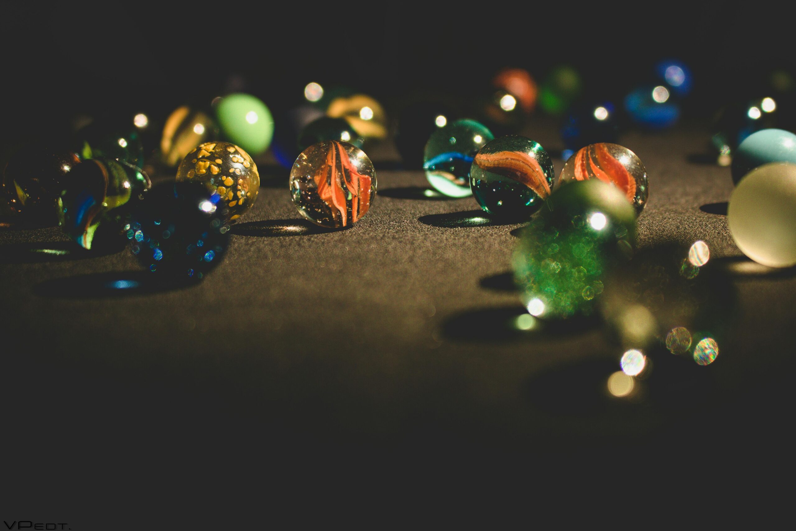 A vibrant collection of glass marbles glistening on a dark surface, showcasing rich colors and textures, alongside Plushy toys.