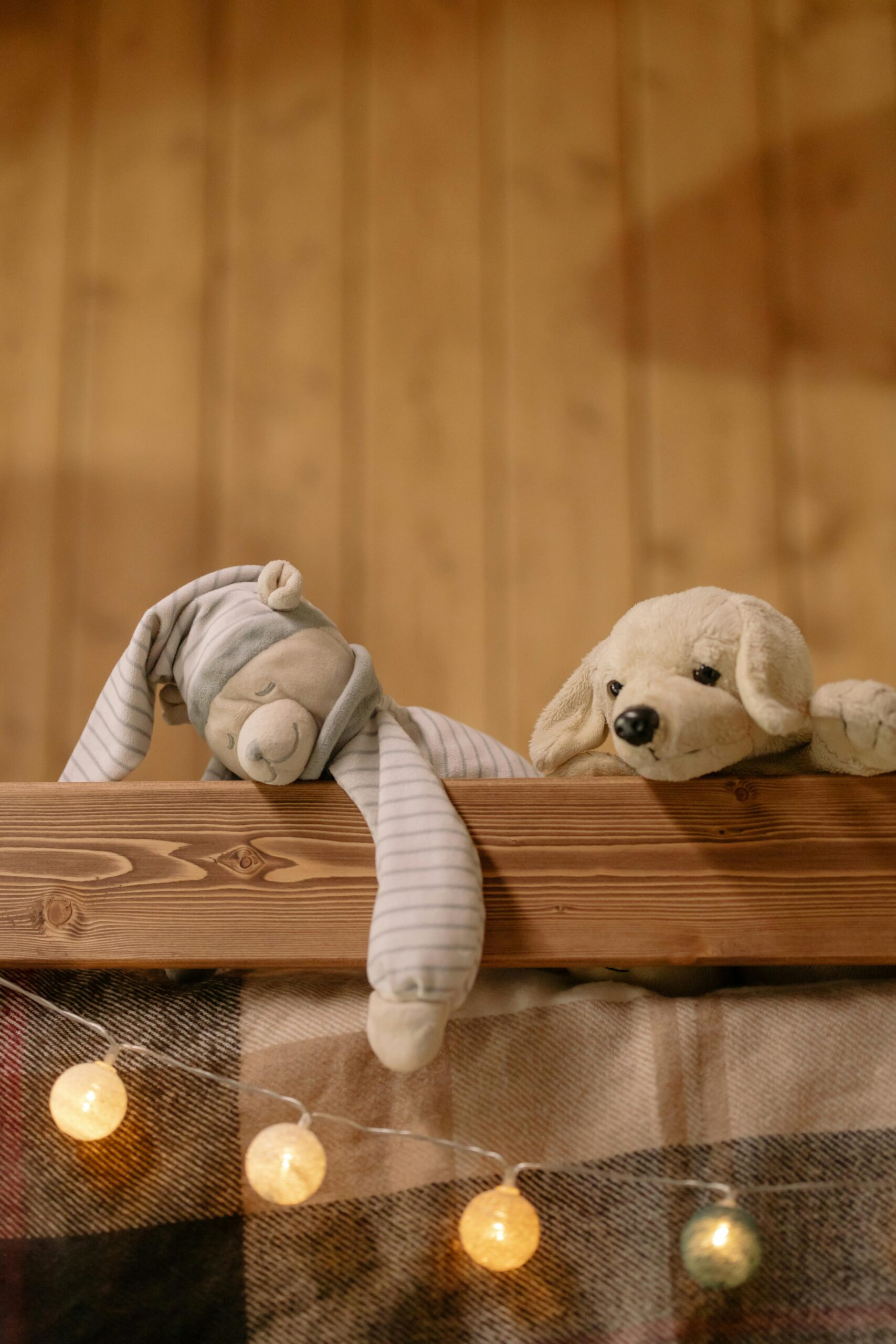 Plush toys in a warm, rustic bedroom setting, enhanced by soft string lights.