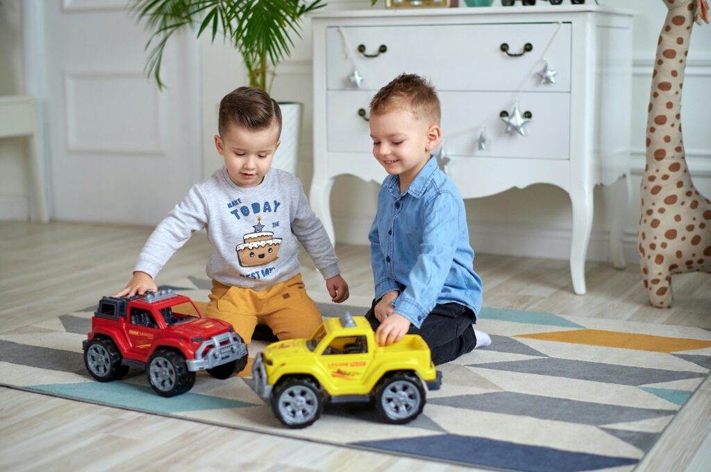 Two young boys enjoy playing with toy cars and play toys in a bright, cozy room.